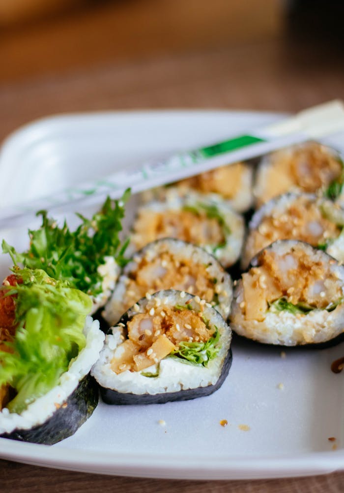 services-02 Close-up of fresh sushi rolls with vegetables on a white plate, perfect for a healthy meal.